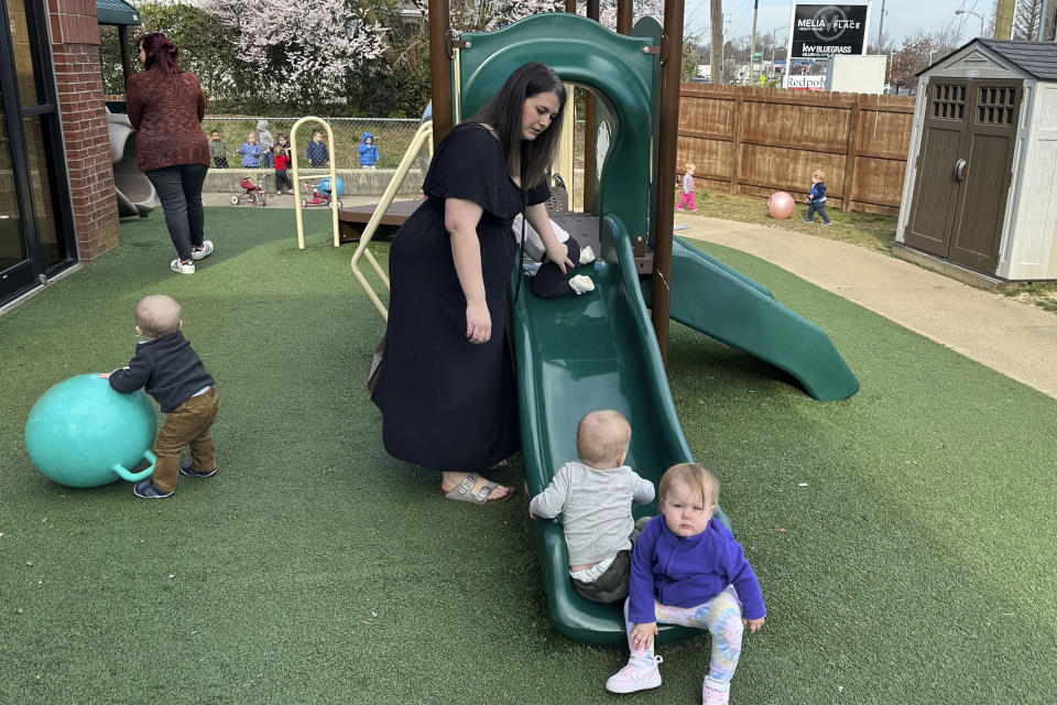 Delaney Griffin, center, plays with toddlers at the child care center where she works, Wednesday, March 13, 2024, in Lexington, Ky. Griffin went to work at the center after leaving a restaurant job because she could receive low cost child care for her daughter. Kentucky started a program in 2023 that offers free child or reduced cost care to child care workers. (AP Photo/Dylan Lovan)