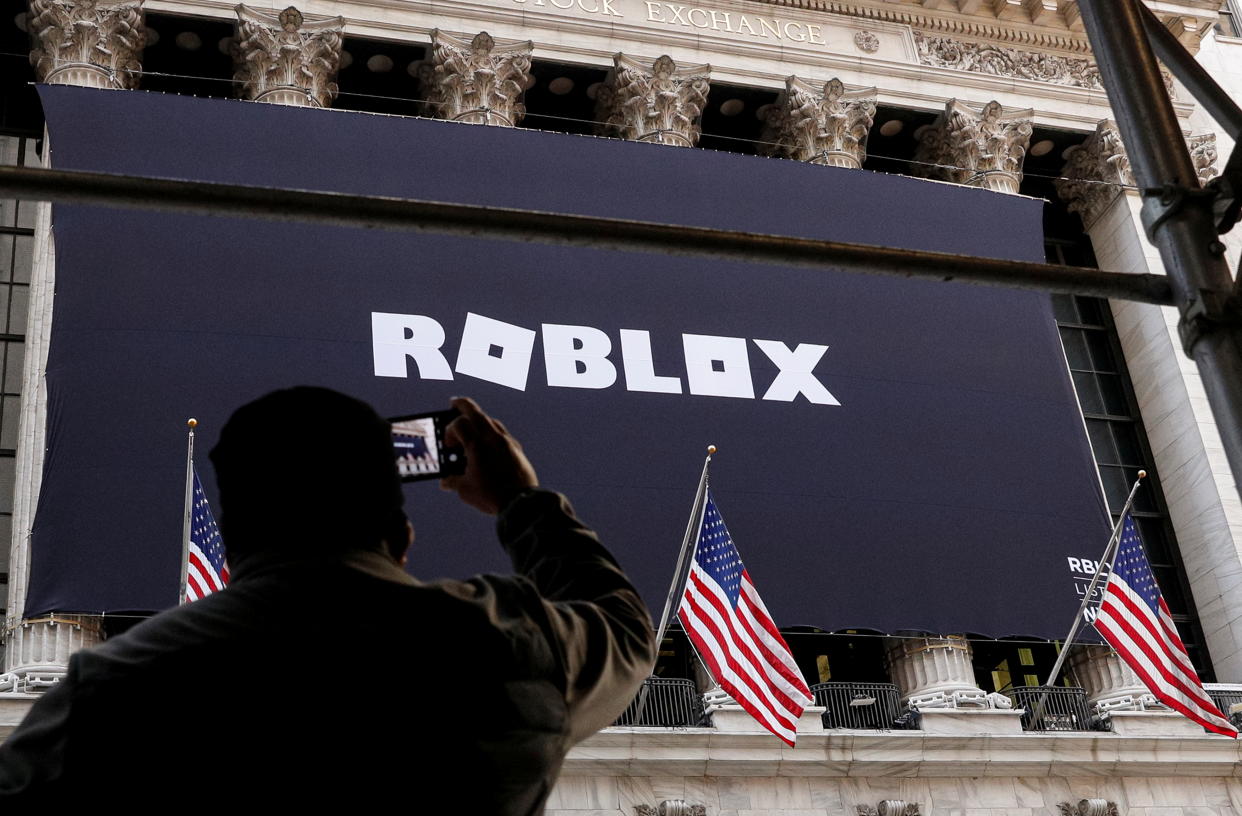 A man photographs a Roblox banner displayed, to celebrate the company's IPO, on the front facade of the New York Stock Exchange (NYSE) in New York, U.S., March 10, 2021. REUTERS/Brendan McDermid