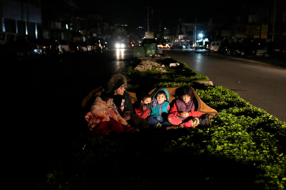 A family sits outside their home in Beirut following an earthquake that hit neighboring Turkey.<span class="copyright">Hussein Malla—AP</span>