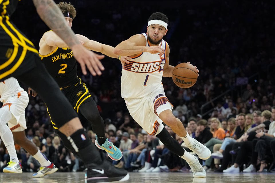 Phoenix Suns guard Devin Booker (1) drives as Golden State Warriors guard Brandin Podziemski (2) defends during the second half of an NBA basketball game, Wednesday, Nov. 22, 2023, in Phoenix. (AP Photo/Matt York)