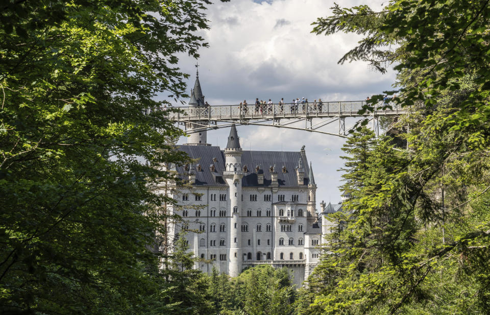 People stay on the Marien-Bridge at Castle Neuschwanstein, a 19th century creation by Bavaria's fairy tale king Ludwig II and world renowned tourist attraction, is pictured in Hohenschwangau near Fuessen, southern Germany, on Thursday, June 15, 2023. Authorities say a tourist has died after a man attacked her and a companion near Neuschwanstein castle in southern Germany. The incident near the popular tourist attraction close to the Austrian border happened Wednesday afternoon. (Frank Rumpenhorst/dpa via AP)