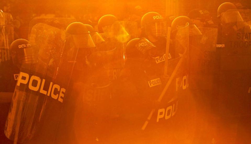 The sun sets as law enforcement officers form a line to push a group of protestors back in the Columbia Vista after a peaceful rally to protest the killing of George Floyd escalated into groups breaking into businesses and burning police cars in the Columbia Vista.