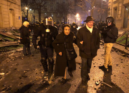 French riot police evacuate an elderly couple near the Arc de Triomphe during clashes with protesters wearing yellow vests, a symbol of a French drivers' protest against higher diesel taxes, in Paris, France, December 1, 2018. REUTERS/Lucien Libert