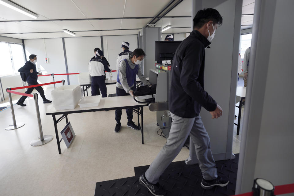 Staffs and security personnel participate in a screening test for spectators and officials to ensure a safe and secure Toyo Olympic Games Wednesday, Oct. 21, 2020, in Tokyo. Tokyo Olympic officials say they don't know exactly what measures will be taken against the COVID-19 pandemic at next year's Games, but they want the world to know they're working on it. (AP Photo/Eugene Hoshiko)