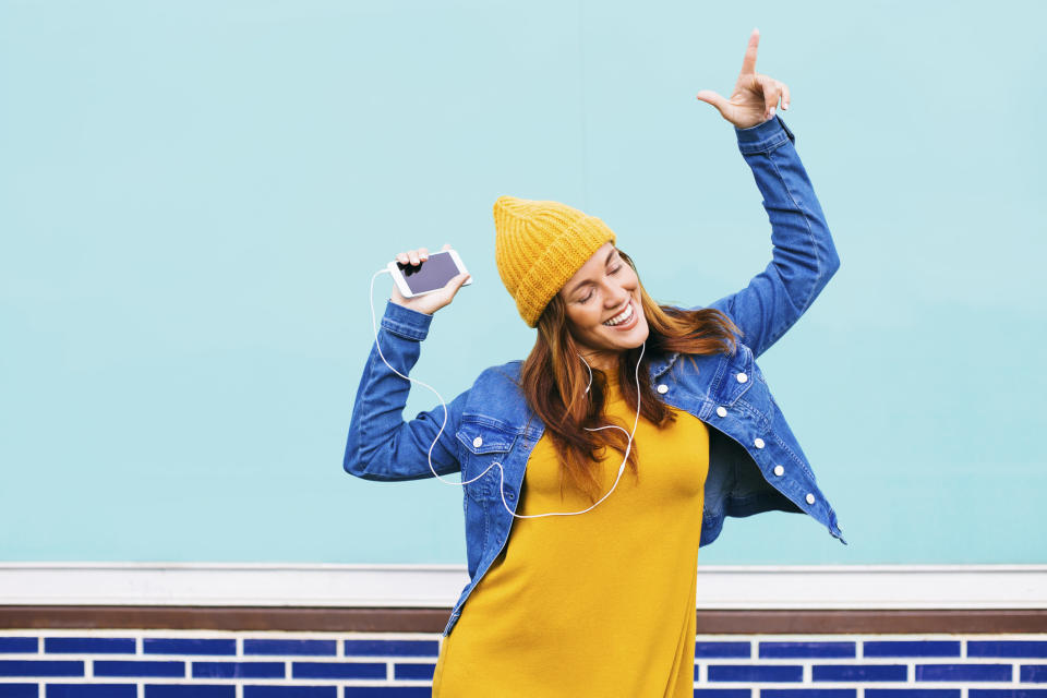 A woman listening to music and wearing a jean jacket