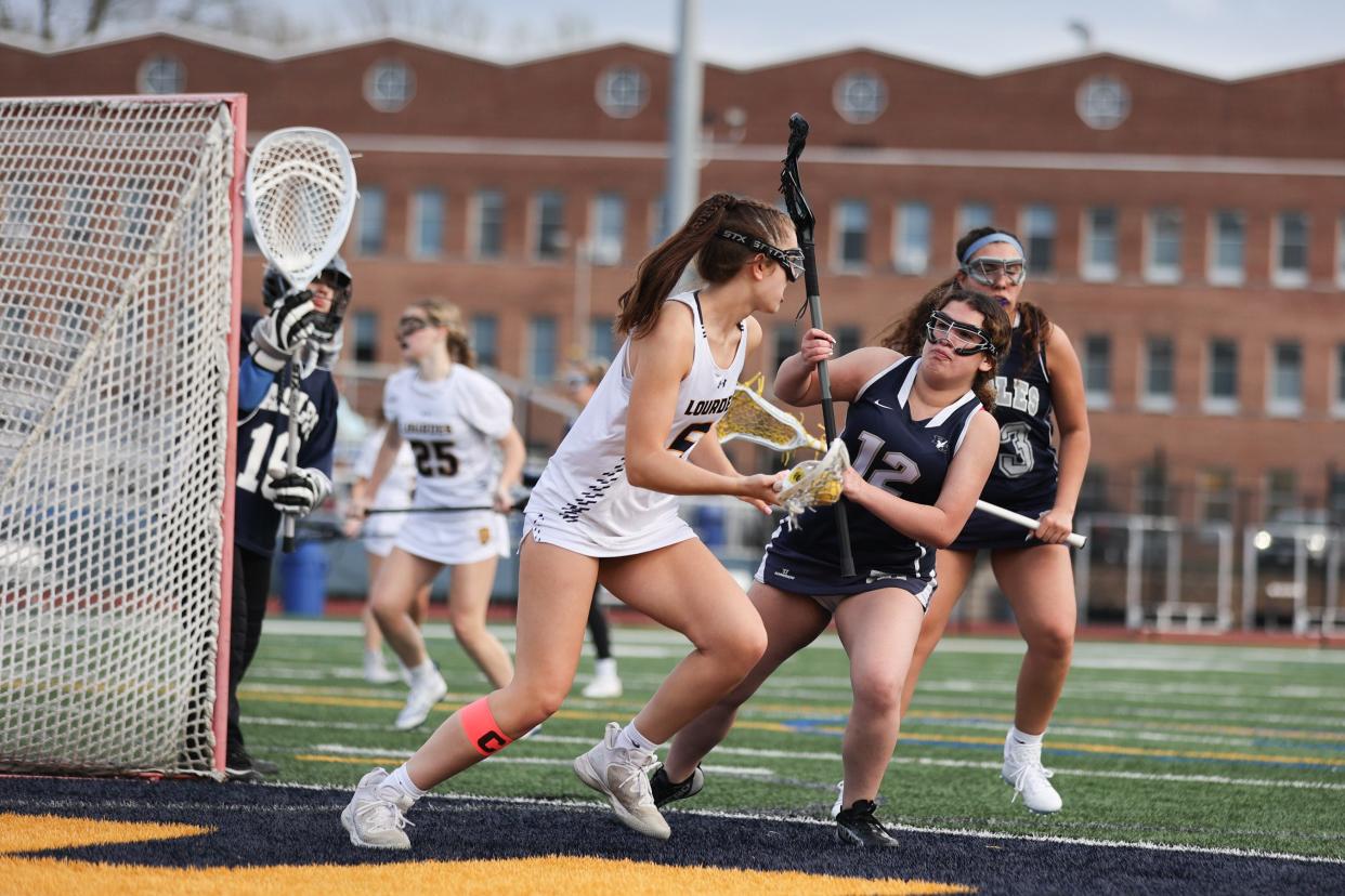 Lourdes' Morgan McHale tries to maneuver around Burke Catholic's Amelia Weinstein during an April 12, 2024 girls lacrosse game.