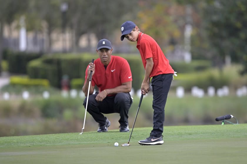 Tiger Woods watches his son Charlie putt on the 18th green during the final round of the PNC Championship golf tournament, Sunday, Dec. 20, 2020, in Orlando, Fla. (AP Photo/Phelan M. Ebenhack)
