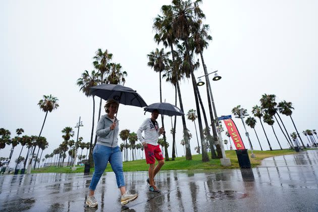 People walk along Venice Beach in the rain on Aug. 20, in Los Angeles.
