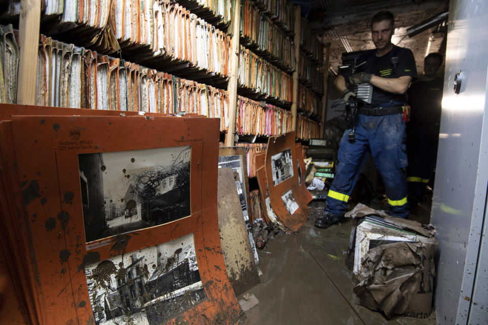 A helper of the Federal Agency for Technical Relief (THW) walks through the flooded city archive in Stolberg, western Germany, Sunday, July 18, 2021. Heavy rains caused mudslides and flooding in the western part of Germany. Multiple have died and are missing as severe flooding in Germany turned streams and streets into raging, debris-filled torrents that swept away cars and toppled houses. (Marius Becker/dpa via AP)