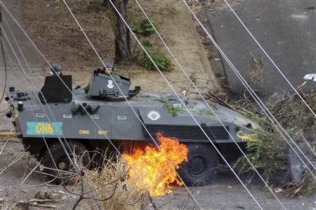 National Guards look on at a fire under the tank they are in, started after the tank was hit by a Molotov cocktail, during a protest against Venezuelan President Nicolas Maduro's government in San Cristobal, about 410 miles (660 km) southwest of Caracas, February 27, 2014. REUTERS/Stringer