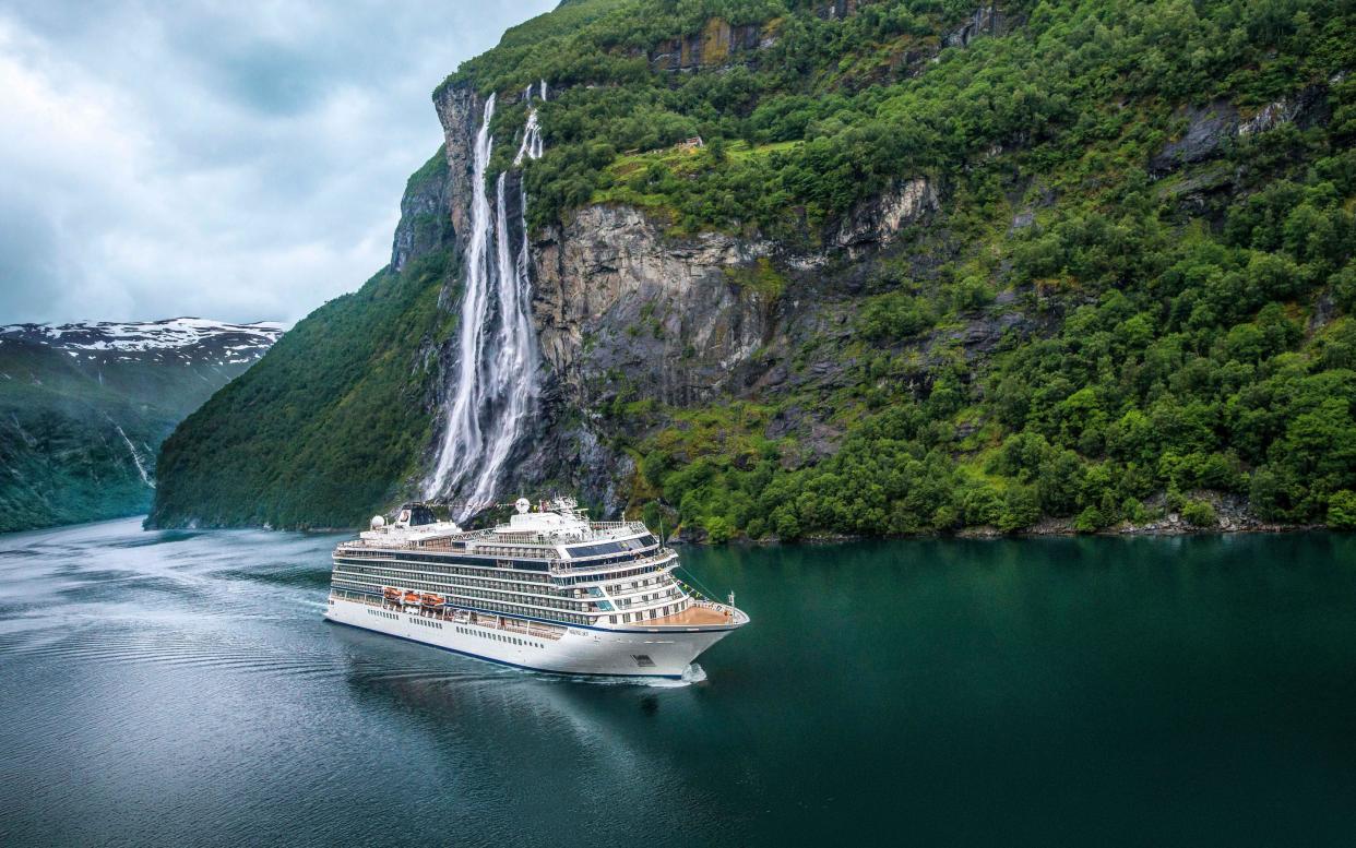A Viking ocean ship sails by the Seven Sisters waterfall in Geirangerfjord - Viking Cruises owns all rights to images for unlimited time and usage/media, worldwide, for all images. Photographer retains right to use images for self-promo on own website, but may not refer to 