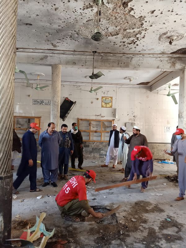 Residents and rescue workers survey the site after a bomb blast at a religious seminary in Peshawar