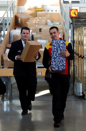 German Labour Minister Hubertus Heil carries a parcel as he visits a German postal and logistics group Deutsche Post DHL parcels distribution centre in Berlin