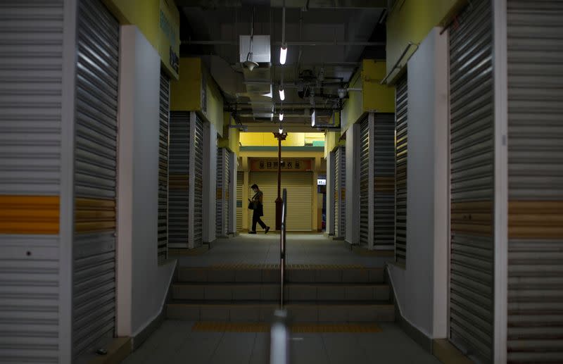 FILE PHOTO: A woman passes closed shops, during the "circuit breaker" measures to curb the coronavirus outbreak (COVID-19), in Singapore's Chinatown