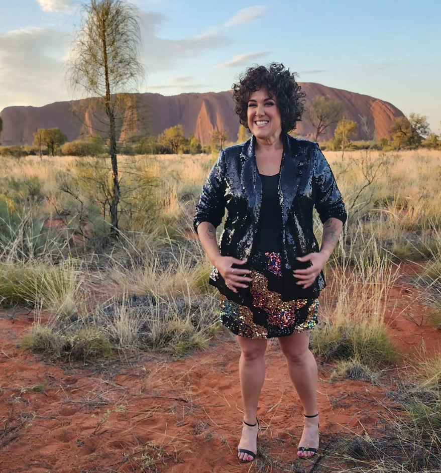 Casey Donovan stands in front of Uluru. 
