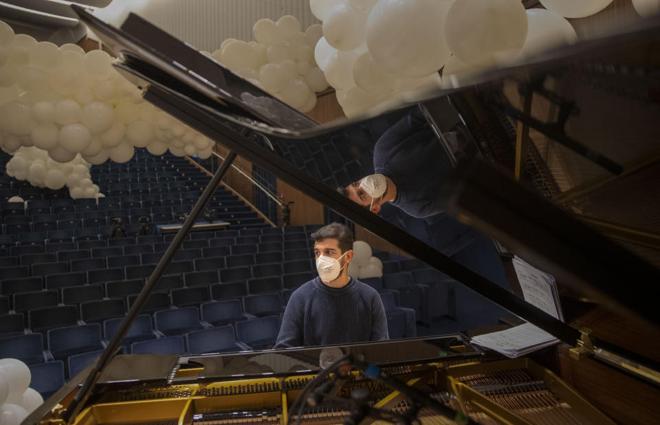 Jazz orchestra musician Claudio Guarcello wears a face mask to curb the spread of COVID-19 before playing a rehearsal at the Giuseppe Verdi Music Conservatory, in Milan, Italy, Friday, May 7, 2021. Whatever the instrument, flute, violin or drums, students at Italy's oldest and largest music conservatory have been playing behind plexiglass screens during much of the pandemic as the Conservatory found ways to preserve instruction throughout Italy’s many rolling lockdowns. (AP Photo/Antonio Calanni)