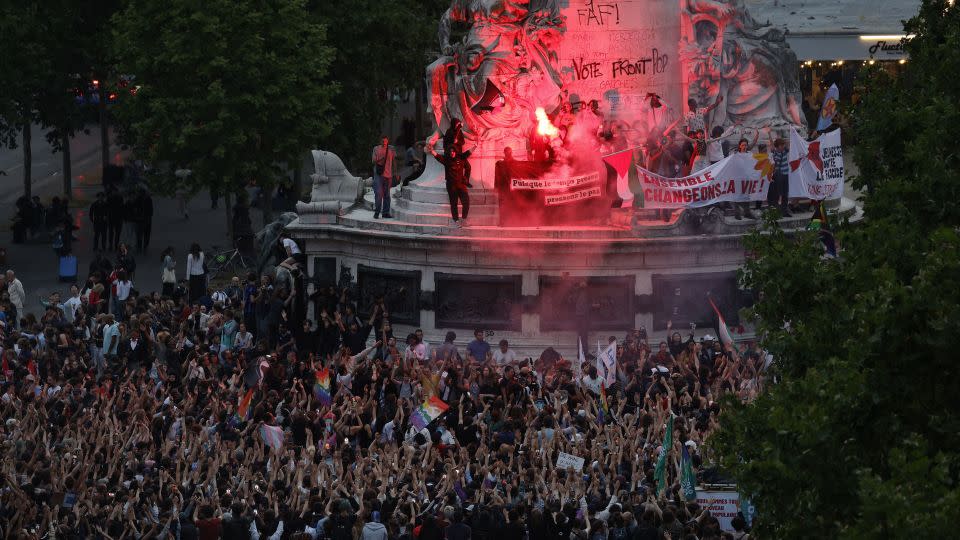 Demonstrators standing on the Monument a la Republique light flares as they take part in a rally after the announcement of the results of the first round of French parliamentary elections, at Place de la Republique in Paris on June 30, 2024. - Geoffroy van der Hasselt/AFP/Getty Images