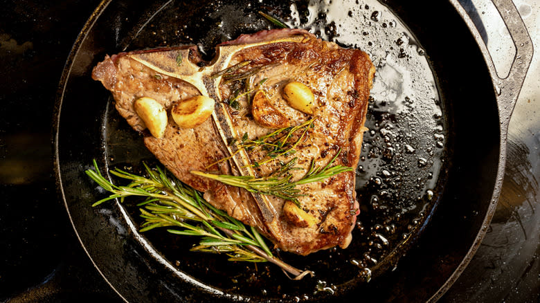 T-bone steak in skillet with herbs