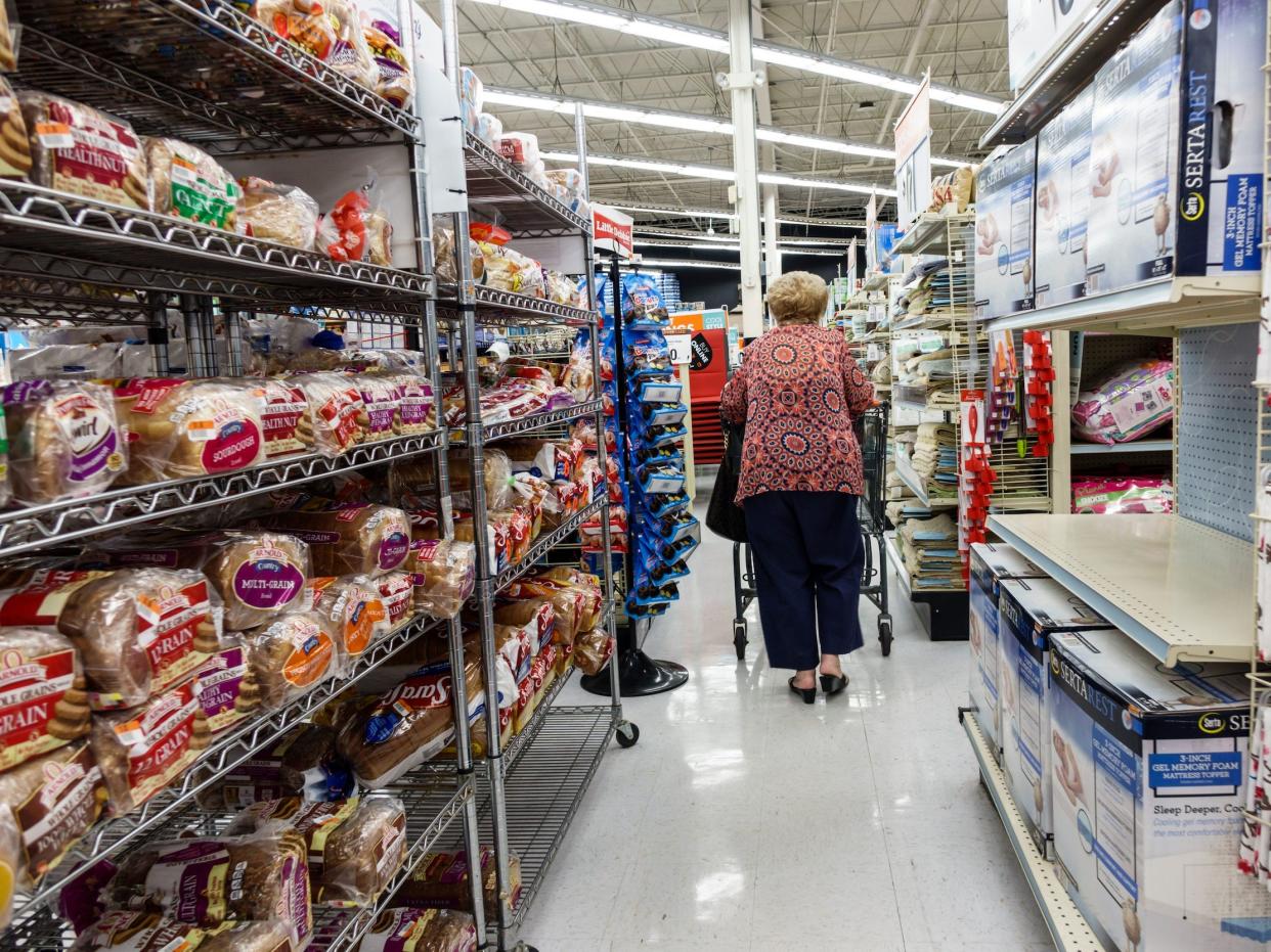 Woman pushes shopping cart down bread aisle at Big Lots store