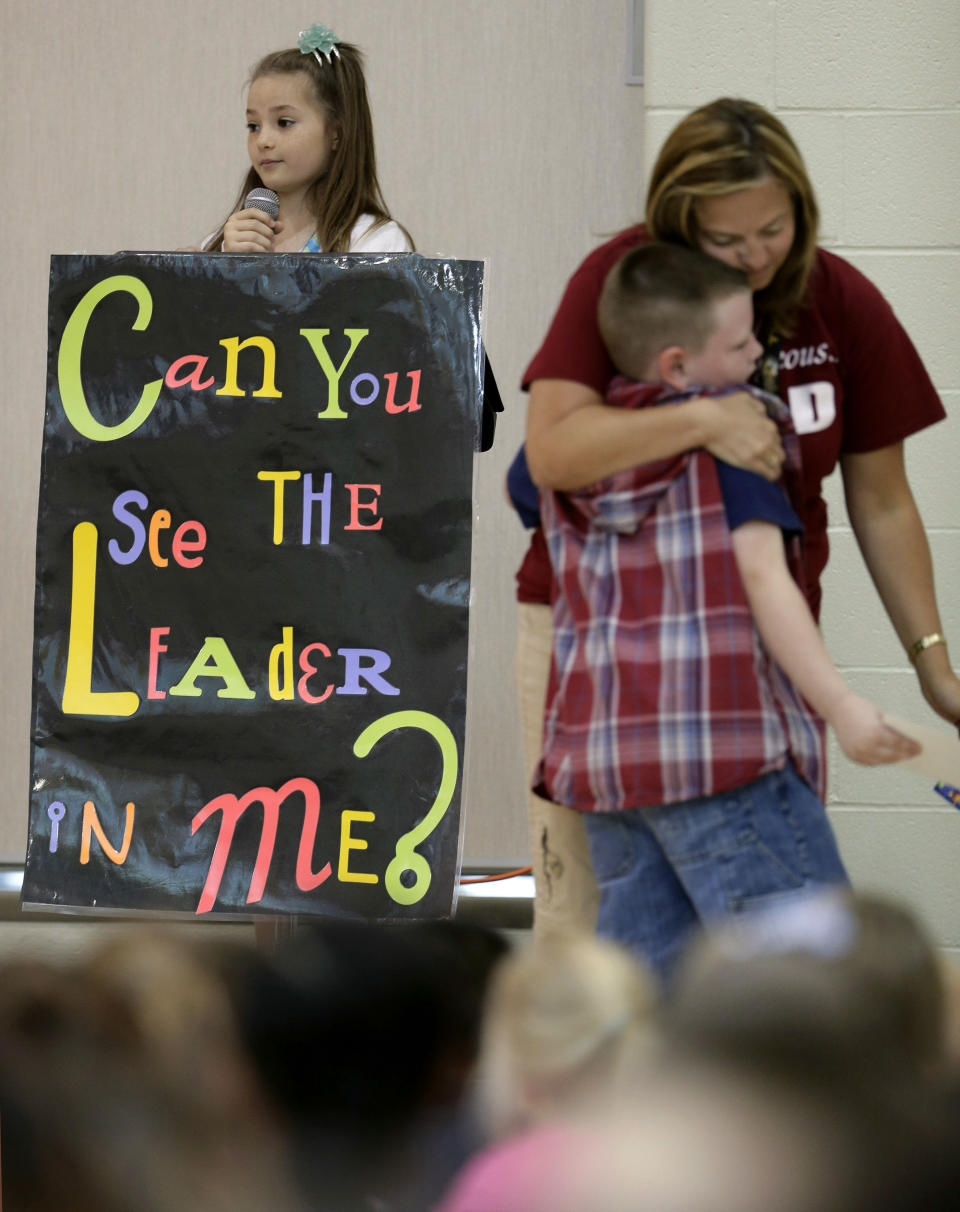 In this photo taken Friday, Sept. 6, 2013, third-grader Jonathan Kent gets a hug from his teacher Mandy Brown after getting an award during a monthly leadership assembly presided over by fourth-grader Anita Bedworth at Indian Trails Elementary school in Independence, Mo. The school is one of 1,400 nationwide utilizing a program called "The Leader in Me" which is based on the late self-help guru Stephen Covey's best-selling "The Seven Habits of Highly Effective People." (AP Photo/Charlie Riedel)