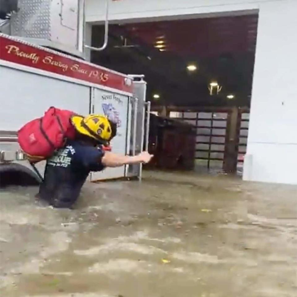 A Naples Fire Rescue Department firefighter carries gear in water from the storm surge  - Naples Fire Department 