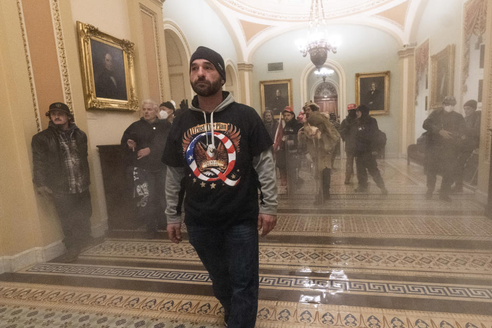 FILE - In this Jan. 6, 2021, file photo, smoke fills the walkway outside the Senate Chamber as supporters of President Donald Trump are confronted by U.S. Capitol Police officers inside the Capitol in Washington. Far-right social media users for weeks openly hinted in widely shared posts that chaos would erupt at the U.S. Capitol while Congress convened to certify the election results. (AP Photo/Manuel Balce Ceneta, File)