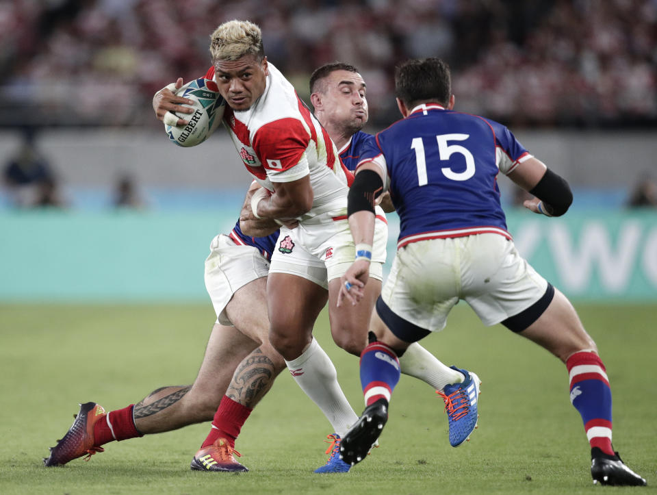 Japan's Lomano Lemeki, left, is tackled by Russia's Vladimir Ostroushko as Russia's Vasily Artemyev, right, watches during the Rugby World Cup Pool A game at Tokyo Stadium between Russia and Japan in Tokyo, Japan, Friday, Sept. 20, 2019. (AP Photo/Jae Hong)