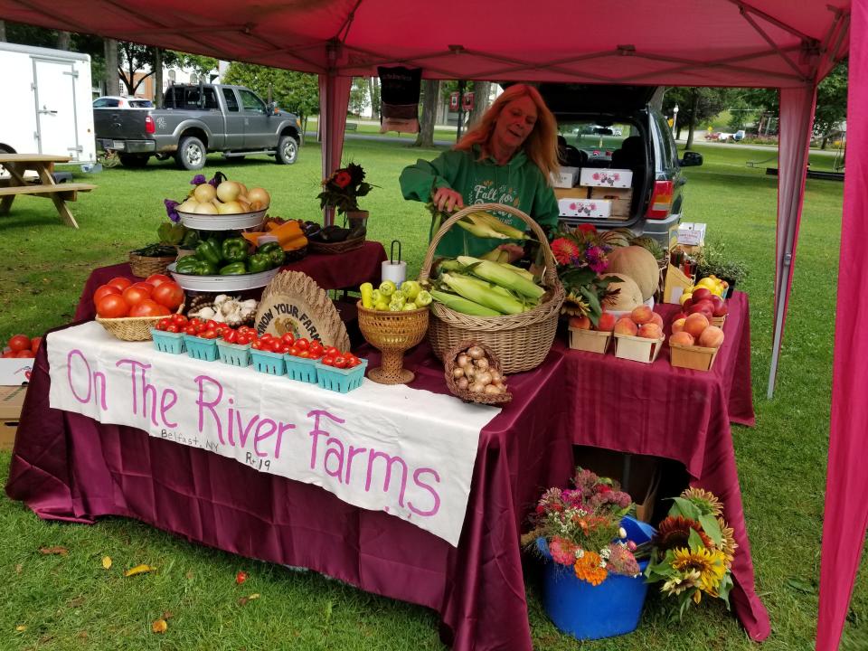 Jan Ruprecht adds produce to the On the River Farms stand at the Angelica Farmers Market.