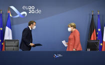 German Chancellor Angela Merkel, right, and French President Emmanuel Macron prepare to address a media conference at the end of an EU summit in Brussels, Tuesday, July 21, 2020. Weary European Union leaders finally clinched an unprecedented budget and coronavirus recovery fund early Tuesday, finding unity after four days and as many nights of fighting and wrangling over money and power in one of their longest summits ever. (John Thys, Pool Photo via AP)