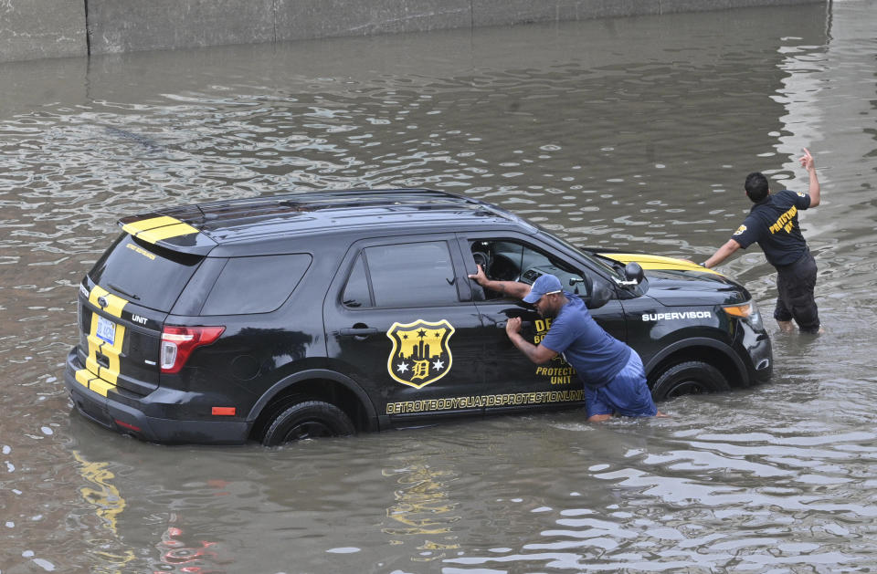A vehicle is pushed out of flood waters along Interstate 75 near Superior Street in Detroit on Saturday, June 26, 2021. (Max Ortiz/Detroit News via AP)