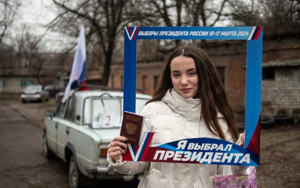 A woman poses in Donetsk after casting her ballot during early voting in Russia's presidential election