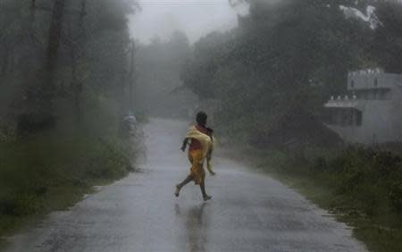 A girl runs for shelter in heavy rain brought by Cyclone Phailin in Ichapuram town in Srikakulam district in Andhra Pradesh October 12, 2013. REUTERS/Adnan Abidi