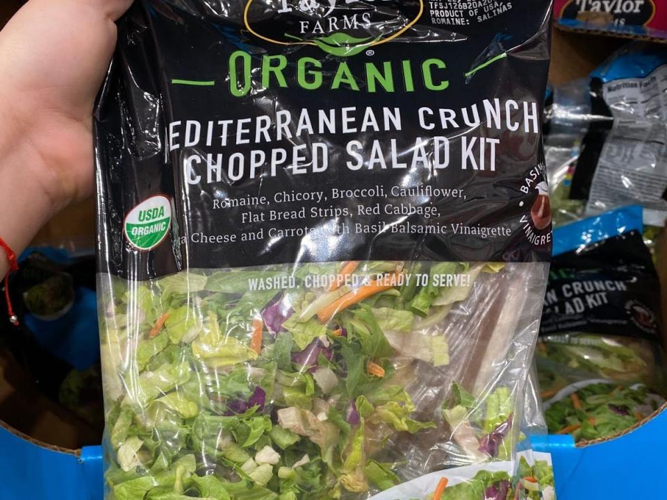 hand holding a bag of costco's organic mediterranean salad mix