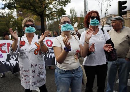 Protesters wear masks reading "Mato Resign" (in reference to Spanish Health Minister Ana Mato) during a demonstration against government spending cuts in the health care sector, outside the Carlos III hospital in Madrid, where a nurse who contracted Ebola is being treated October 8, 2014. REUTERS/Paul Hanna