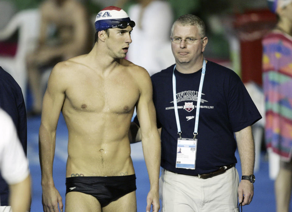 FILE - U.S. swimming star Michael Phelps, left, walks with his coach Bob Bowman during a training session at the World Swimming Championships in Melbourne, Australia. Given that Michael Phelps won 23 gold medals at the Olympics, Bowman had little reason to question his over-the-top techniques. (AP Photo/Mark Baker, File)