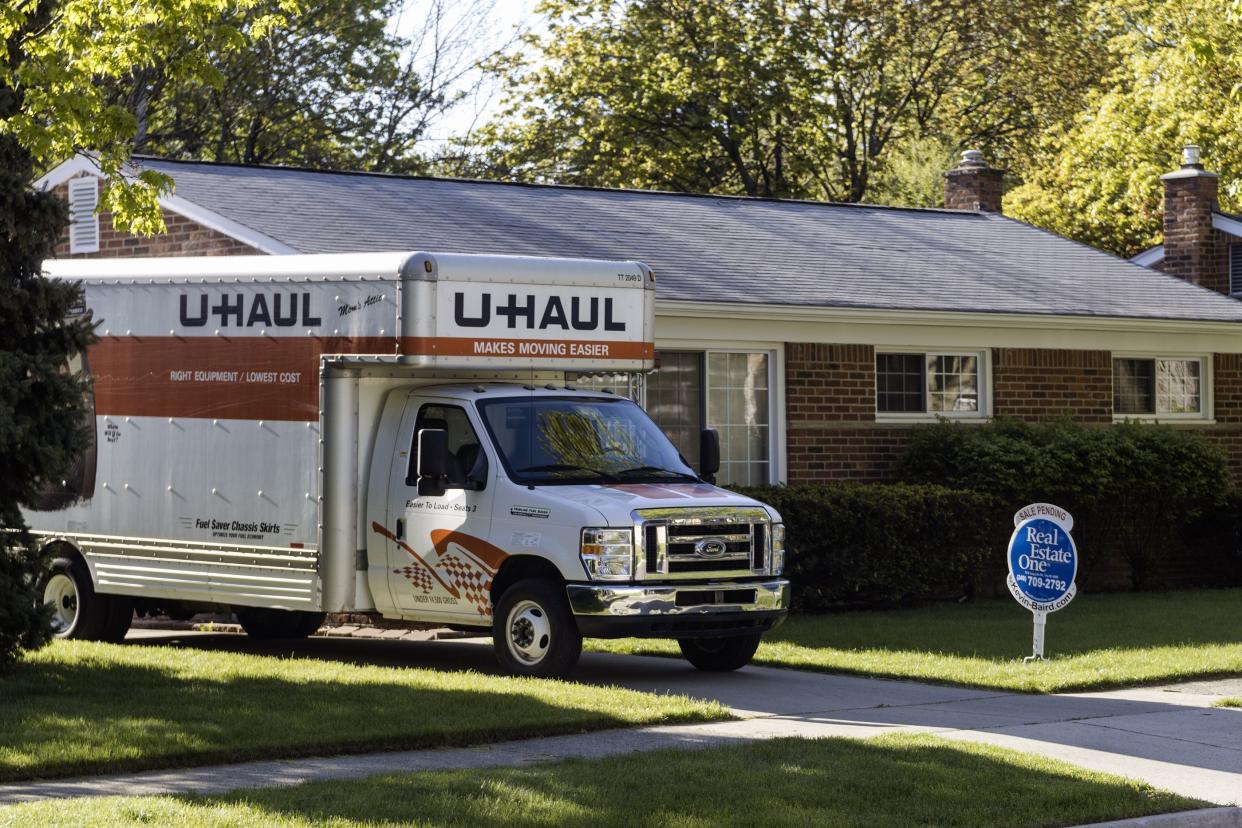 moving van outside home with real estate sign