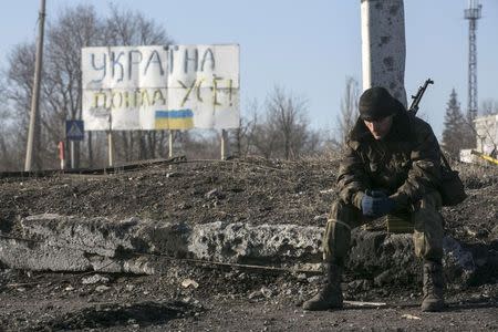 A fighter with the separatist self-proclaimed Donetsk People's Republic army sits in front of a sign reading "Ukrainian over all" at a check point in Debaltseve, February 20, 2015. REUTERS/Baz Ratner