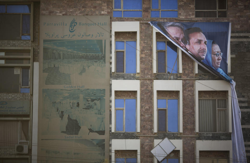 In this Monday, March 10, 2014 photo, a banner with Afghan presidential candidate Zalmai Rassoul, from left, and his two vice presidents Ahmad Zia Masoud and Habiba Surabi in Kabul, Afghanistan. Rassoul took the bold step of choosing a woman as one of his two running mates - seeking to appeal to female voters. Still he, too, has the support of those with a bloody past, including former loyalists of Hezb-e-Islami leader Gulbuddin Hekmatyar, also blamed for widespread carnage during Afghanistan’s civil war. (AP Photo/Anja Niedringhaus)