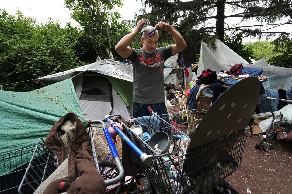 Adam Sutphin, 46, combs his hair as he looks into a mirror outside his tent Monday at a homeless camp near the now-closed Heer Park. He is among those the city intends to evict on June 14.