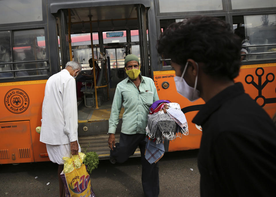 A vendor selling face masks disembarks a bus as he looks for prospective buyers at a bus station in Bengaluru, India, Tuesday, Jan. 5, 2021. India authorized two COVID-19 vaccines on Sunday, paving the way for a huge inoculation program to stem the coronavirus pandemic in the world's second most populous country. (AP Photo/Aijaz Rahi)