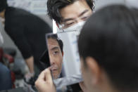 Yoshihiro Kamichi, a 44-year-old office worker, checks his face in a mirror as he receives makeup and gets his hair done by a makeup artist at Ikemen-Works, a makeup salon for men, in Tokyo Wednesday, Feb. 3, 2021. The coronavirus pandemic has been pushing businesses to the edge in Japan, but some in the men's beauty industry have seen an unexpected expansion in their customer base. Japanese businessmen in their 40s, 50s and 60s who had little interest in cosmetics before the pandemic are now buying makeup. (AP Photo/Eugene Hoshiko)