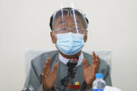 Myint Naing, a member of the Union Election Commission, wearing a protective face mask and shield gestures during a press conference in Naypyitaw, Myanmar, Tuesday, Oct. 20, 2020. Myanmar’s official election supervisory body on Tuesday defended its decision to cancel voting in several areas in next month’s election, saying it could not be free and fair because of ongoing conflicts with armed ethnic rebel groups. (AP Photo/Aung Shine Oo)