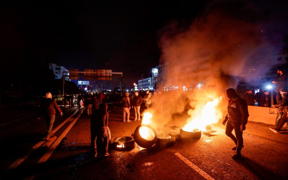 Protesters set tires on fire as they demonstrate against the newly-announced government - AFP