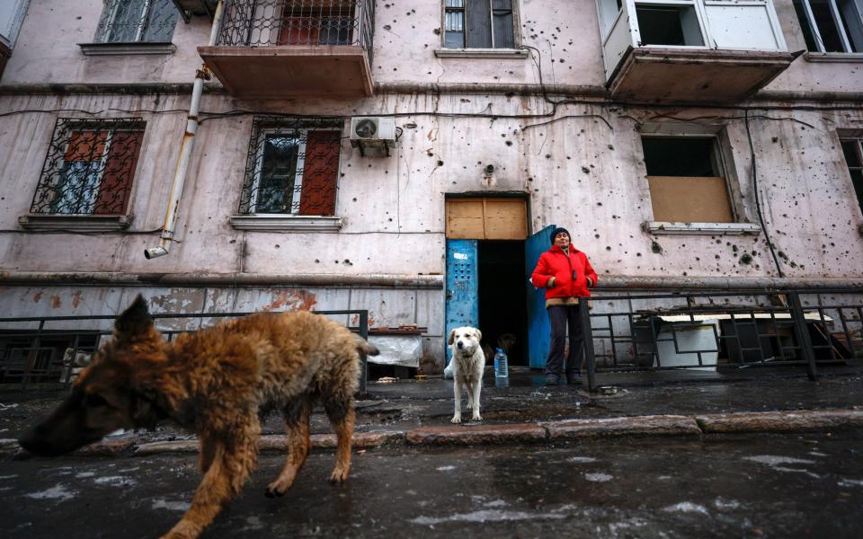 Zhanna, 74, stands next to the entrance to the shelter of a damaged building in Mariupol, Ukraine - SERGEI ILNITSKY/EPA-EFE/Shutterstock