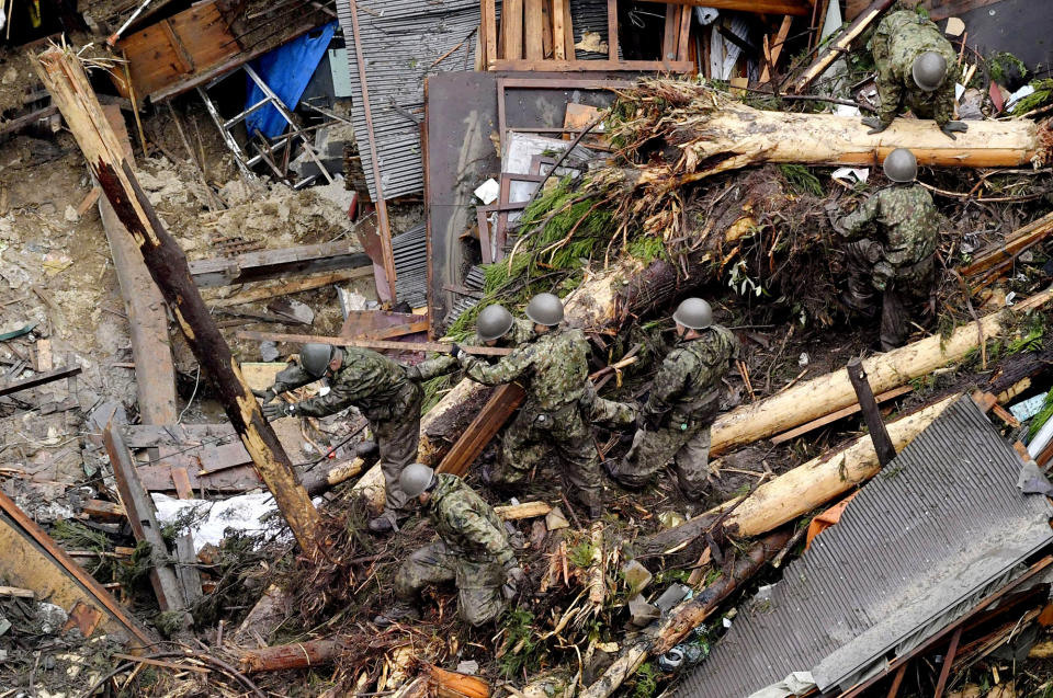<p>Rescue workers from Japan’s Self Defense Force search through debris piled over a house completely demolished by flooding caused by heavy rain in Toho, Fukuoka prefecture, southwestern Japan Thursday, July 6, 2017. Troops worked Thursday to rescue hundreds of people stranded by flooding in southern Japan. (Photo: Nozomu Endo/Kyodo News via AP) </p>