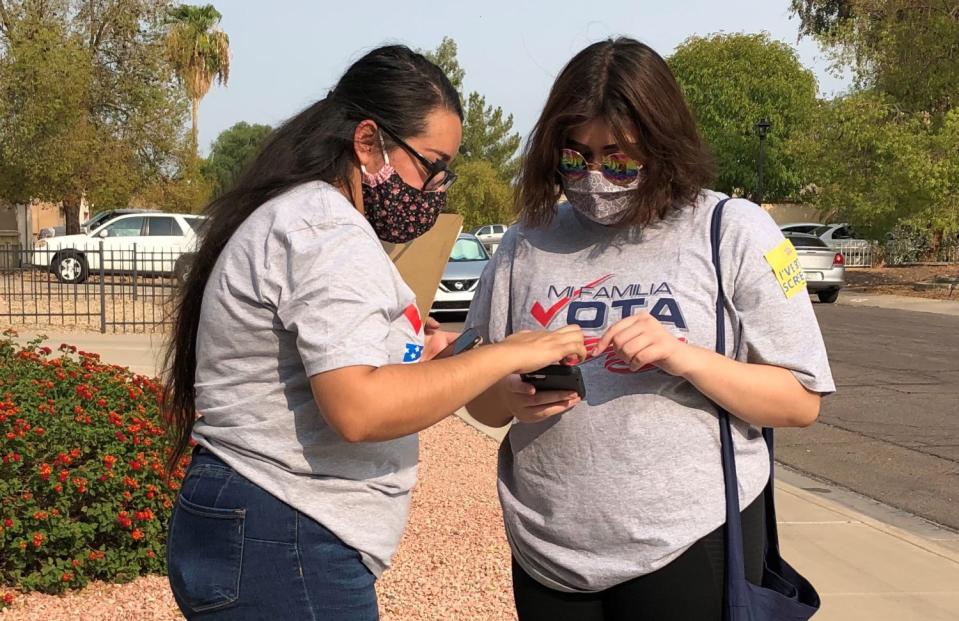 Areli Arteaga, left, and Melissa Galindo wear masks while standing outside in Phoenix.