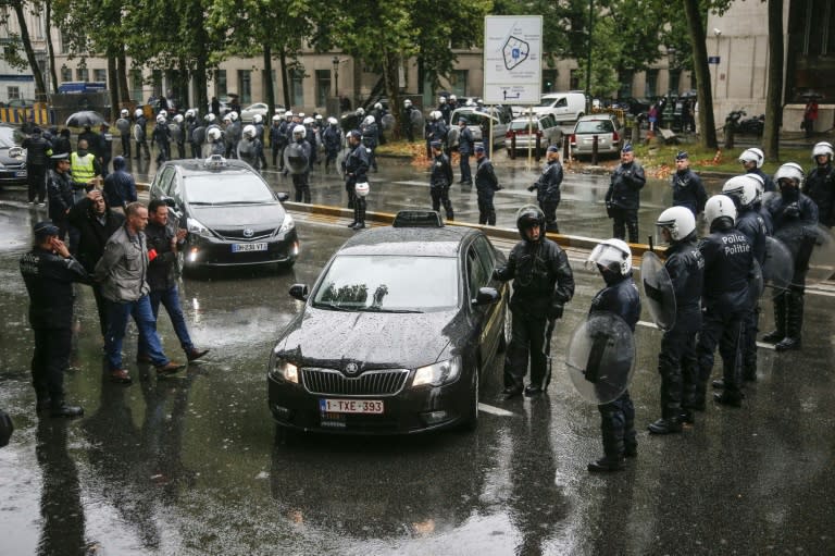 Taxi drivers face riot police during a protest against the controversial ride-sharing app Uber in Brussels on September 16, 2015