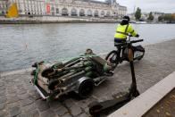 An employee of bicycle sharing service Lime patrols to fish abandoned electric scooters out of the River Seine in Paris