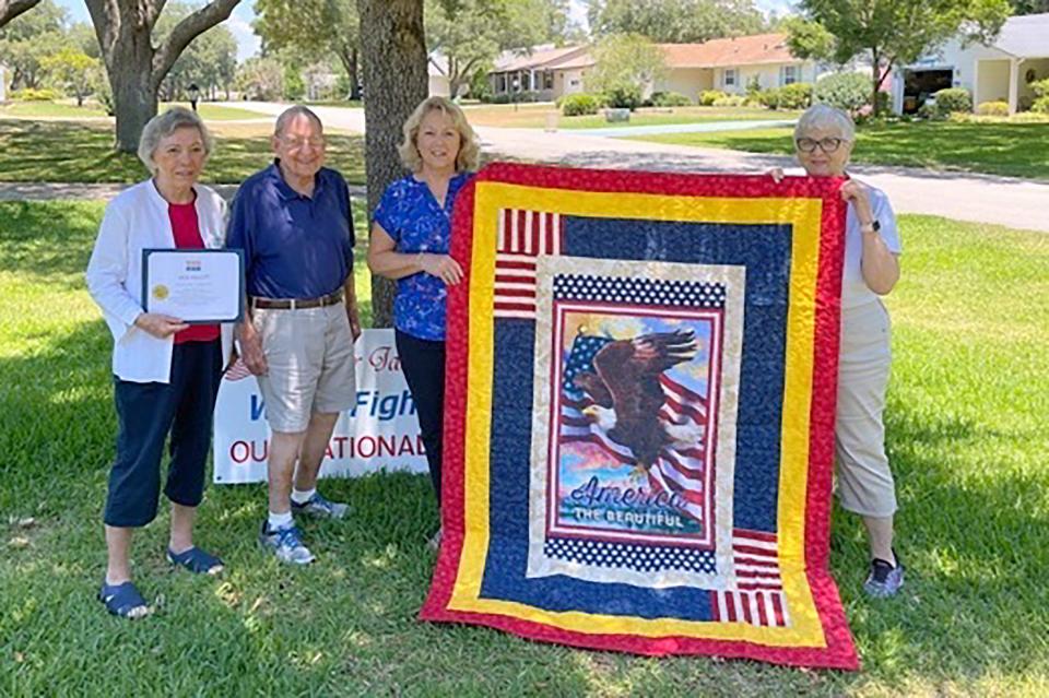 B.J. Hauserman, Pam Beightol and Joan Leubbers of the Ocklawaha Chapter of the Daughters of the American Revolution present the Quilt of Valor to Major Jack Hallett.