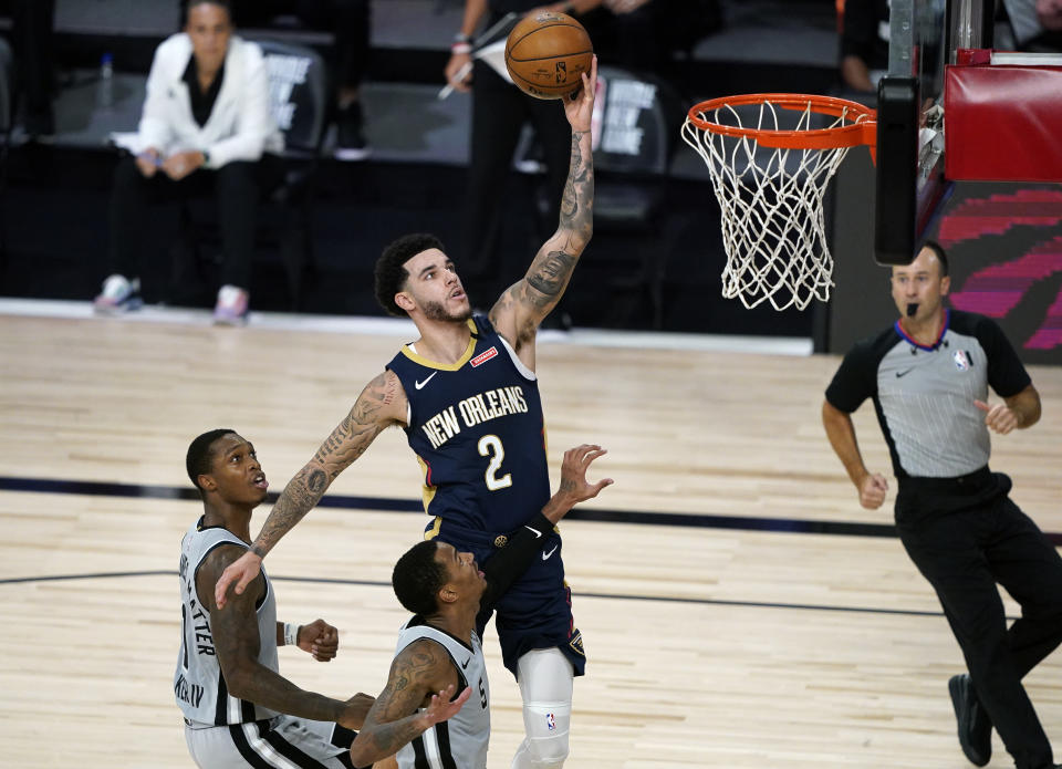 New Orleans Pelicans guard Lonzo Ball (2) makes a shot as he gets between San Antonio Spurs' Lonnie Walker IV, left, and guard Dejounte Murray, center, during the second half of an NBA basketball game, Sunday, Aug. 9, 2020, in Lake Buena Vista, Fla. (AP Photo/Ashley Landis, Pool)